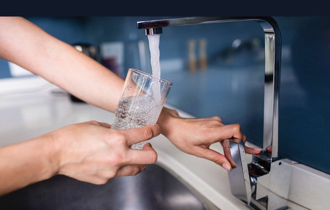 Women fill glass of water from faucet